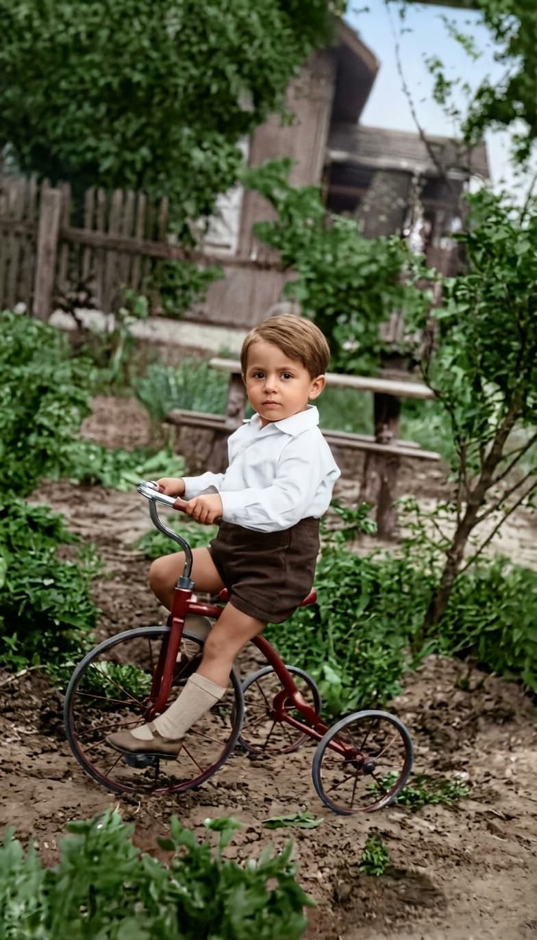 The same boy on his red tricycle after restoration, with natural garden color