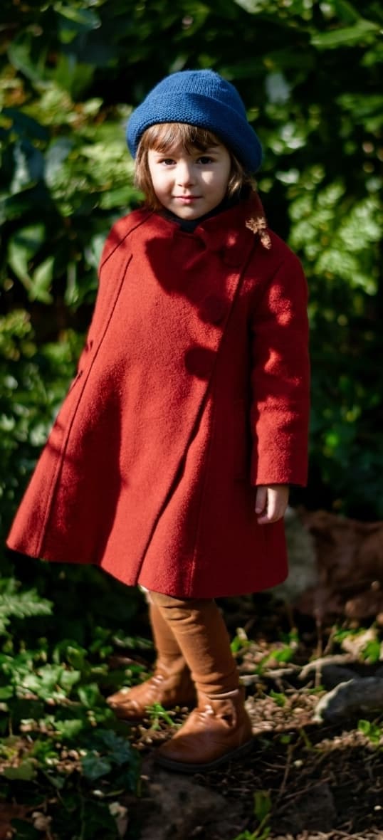 The same photo restored: a young girl in a red wool coat and blue knitted hat