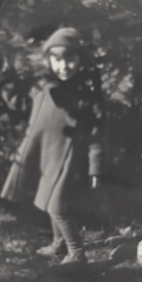 Dark, blurred black-and-white snapshot of a young girl in a coat and hat